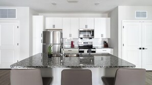 A modern kitchen with white cabinets, stainless steel appliances, and a granite countertop. - Landing | Beautiful 2BD, Gym, Pool (Palm Bay)
