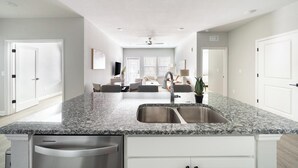 A modern kitchen with granite countertops, stainless steel appliances, and a central island with a sink. - Landing | Beautiful 2BD, Gym, Pool (Palm Bay)