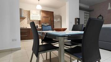 A dining area with a table, chairs, and a kitchen in the background.