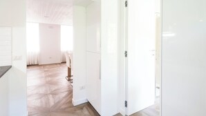 Ein heller, moderner Raum mit Holzboden, weißen Wänden und einem großen Kleiderschrank.