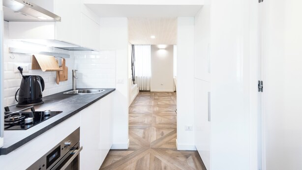 Eine moderne Küche mit weißen Schränken, einer schwarzen Arbeitsplatte und Holzboden.