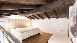 Ein Schlafzimmer mit Holzboden, einem Bett, einem weißen Nachttisch und einer Heizung.