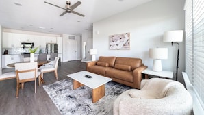 A modern living room with a brown leather sofa, a white coffee table, and a gray rug.