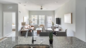 Een moderne keuken met granieten werkbladen, een roestvrijstalen spoelbak en een eethoek met een ronde tafel en stoelen.