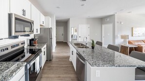 Een moderne keuken met granieten aanrechtbladen, roestvrijstalen apparatuur en een centraal eiland.
