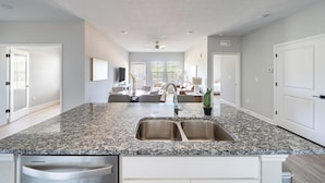 Une cuisine spacieuse dotée de plans de travail en granit, d’un évier double et d’un coin repas avec une table et des chaises.