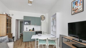 Un espacio habitable compacto con kitchenette, comedor, televisor y sofá.