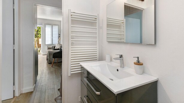 Un baño moderno con lavamanos, espejo y toallero blancos.