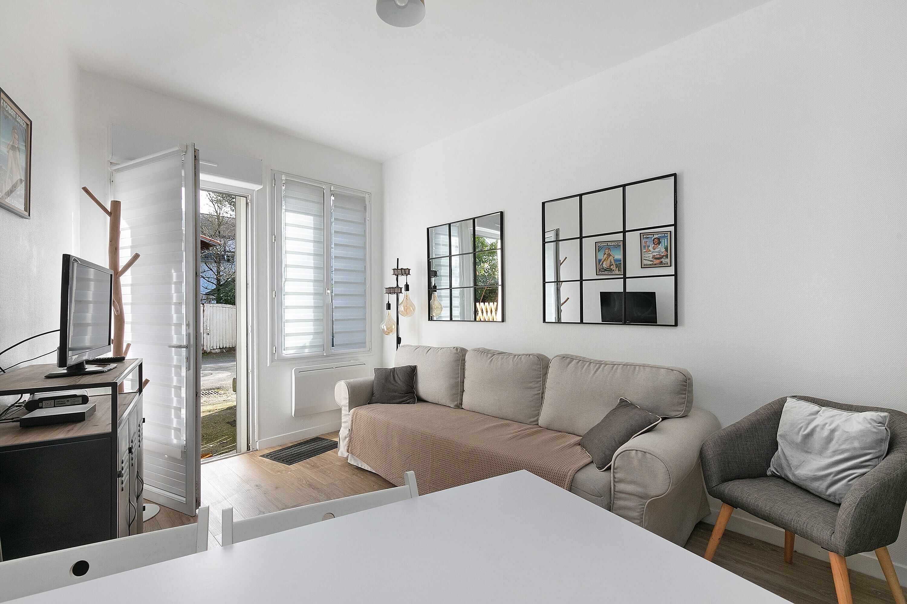 Een moderne woonkamer met een bank, fauteuils, een salontafel en een televisie.