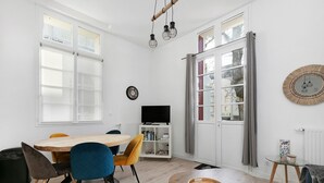 Ein modernes Wohnzimmer mit Esstisch, Stühlen, Fernseher und Bücherregal.