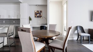 Una cocina moderna con armarios blancos, un comedor con una mesa redonda de madera y cuatro sillas, y una isla de cocina con estufa integrada.