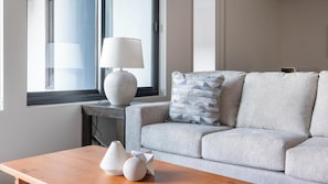 Un salon moderne avec un canapé gris, une table basse en bois et une lampe sur une table d’appoint.