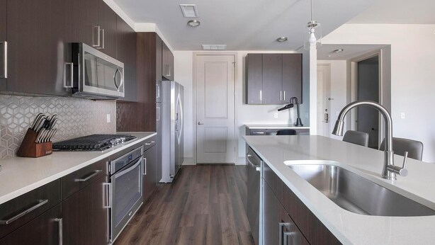 A modern kitchen with stainless steel appliances, a central island with a sink, and a microwave above the stove. - Landing | Spectacular 2BD, Gym, Pool (Houston)