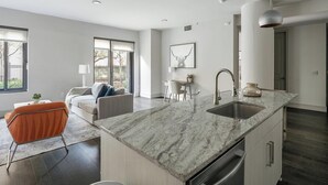 Una cocina moderna con encimera de mármol, pileta de acero inoxidable y lavavajillas integrado.