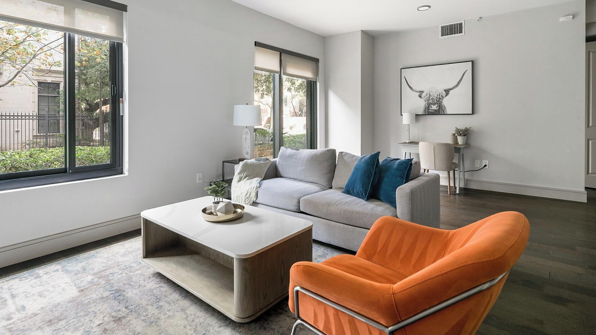 Una sala de estar moderna con un sofá gris, un sillón naranja y una mesa de centro.