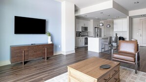 A modern living room with a flat-screen TV, a wooden coffee table, and a leather armchair. - Landing | Incredible 2BD, Tennis Court, Pool (Houston)
