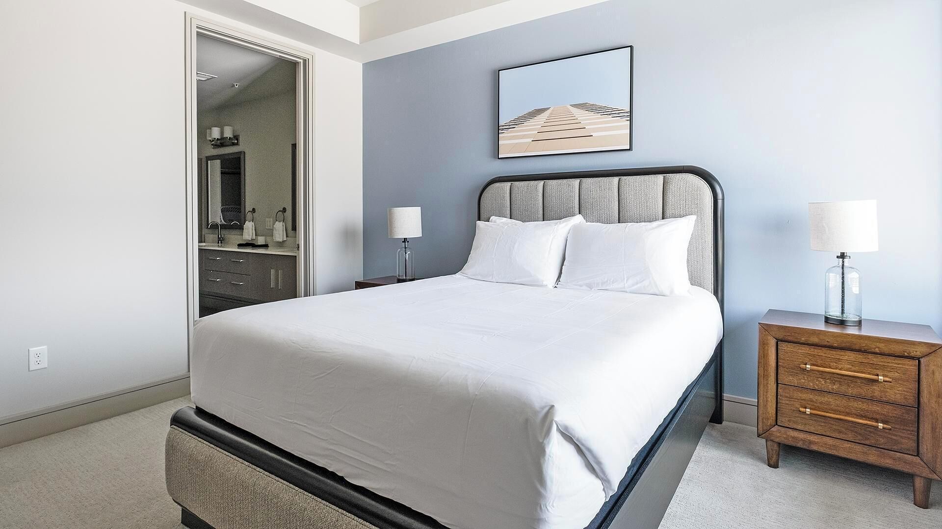 A bedroom with a bed, bedside tables, a dresser, and a framed picture on the wall.