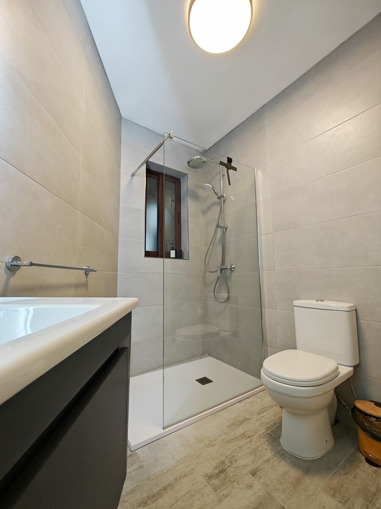 A modern bathroom with a glass-enclosed shower, a white toilet, and a large sink.