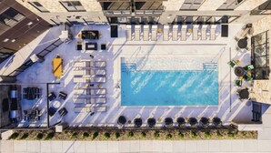 An aerial view of a rooftop pool area with a swimming pool, sun loungers, and a seating area. - Landing | Chic 1BD, Pool, Courtyard (Kansas City)