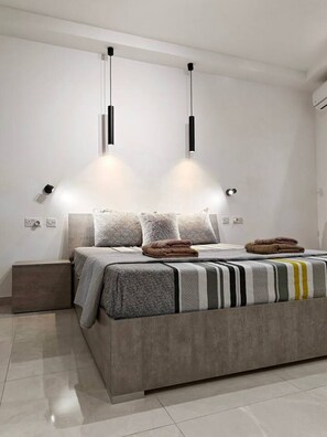 A modern bedroom with a large bed, two pendant lights, and a nightstand. - Valley view 1  2 bedroom aparment (Luqa)