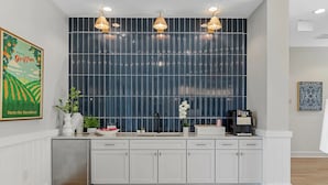 Une cuisine moderne avec des meubles blancs, un pare-feu foncé et des luminaires suspendus.