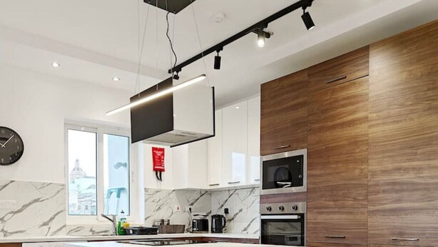 A modern kitchen with a marble island, wooden cabinets, and a built-in oven. - Valley view 2  2 bedroom aparment (Luqa)