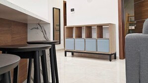 A modern kitchen with a marble backsplash, black bar stools, and a wooden cabinet with blue doors. - Valley view 2  2 bedroom aparment (Luqa)