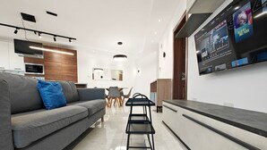A modern living room with a grey sofa, a coffee table, and a TV mounted on the wall. - Valley view 2  2 bedroom aparment (Luqa)