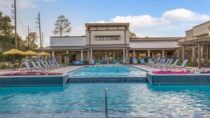 A swimming pool with lounge chairs and umbrellas, a building with a flat roof, and a clear sky. - Landing | Amazing 1BD, Pool, Gym (Houston)