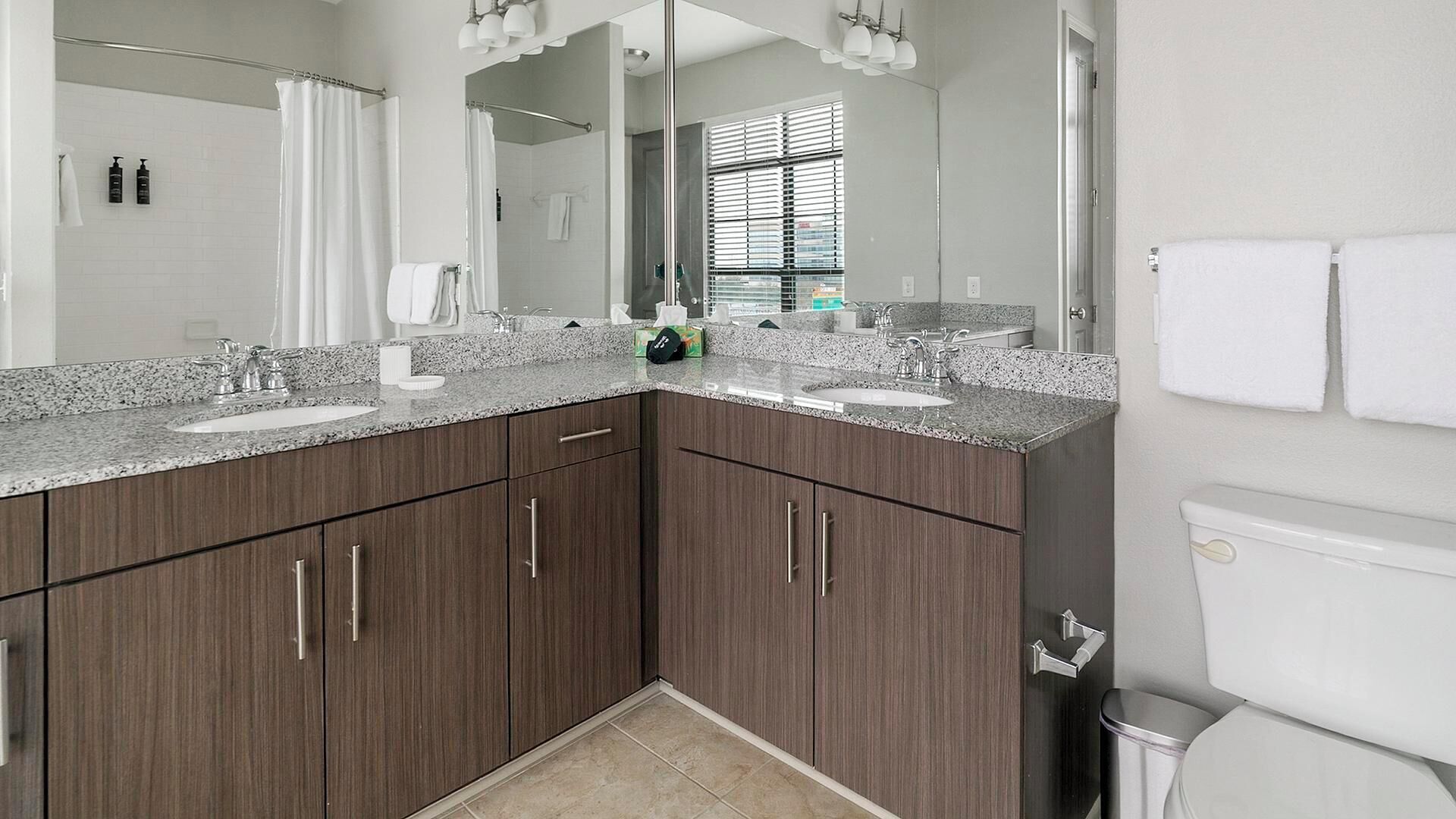 A modern bathroom with two sinks, dark wood cabinets, and a large mirror.