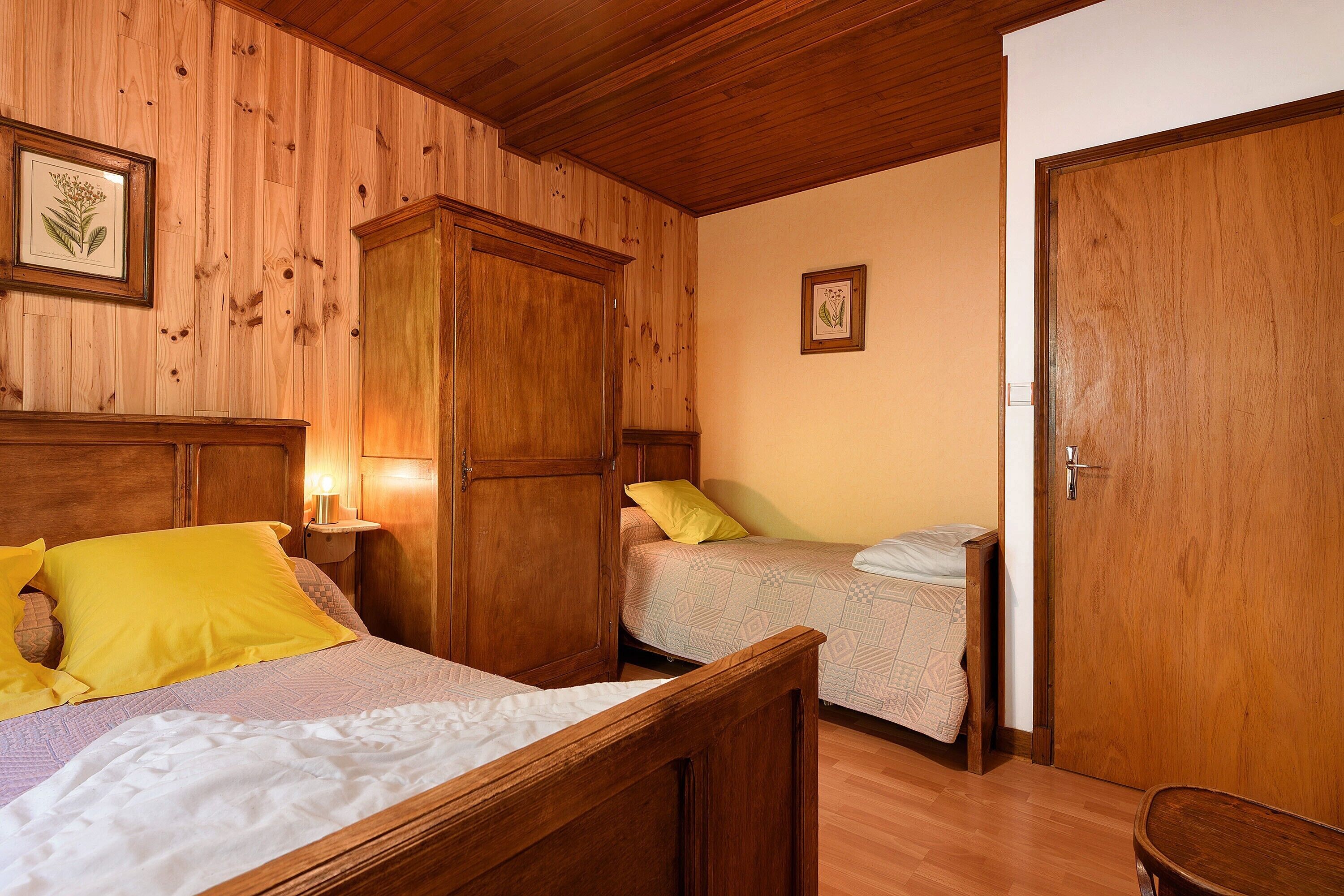 Habitació amb dos llits, parets de fusta, un armari de fusta i una porta.