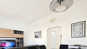 Ein moderner Essbereich mit einem rechteckigen Tisch, schwarzen Stühlen und einer außergewöhnlichen Pendelleuchte aus Draht.