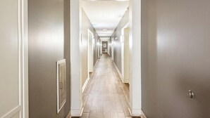 A long, narrow hallway with light-colored walls and wooden flooring. - Landing | Stunning 2BD, Gym, Clubhouse (Norfolk)