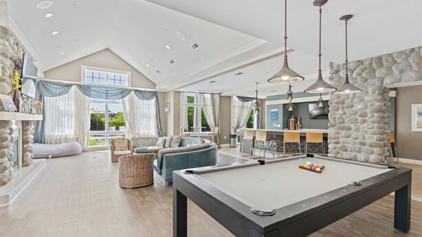 A spacious living room with a pool table, comfortable seating, and a stone accent wall. - Landing | Stunning 2BD, Gym, Clubhouse (Norfolk)