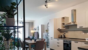 Une cuisine moderne avec un coin repas, dotée d’un sol en marbre, d’appareils électroménagers intégrés et d’une cloison en verre agrémentée de plantes.