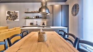 Una cocina moderna con una mesa de comedor de madera, sillas y una lámpara colgante original.