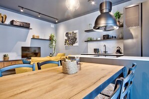 Une cuisine moderne dotée d’une cuisinière intégrée, d’un évier et d’un coin repas avec une table en bois et des chaises bleues.