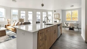A modern kitchen with a large island, built-in appliances, and ample natural light from large windows. - Landing | Amazing 2BD, Gym (Portland)