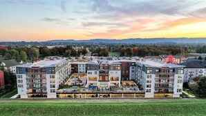 A modern apartment complex with multiple buildings, a rooftop pool, and a view of the surrounding landscape. - Landing | Amazing 2BD, Gym (Portland)