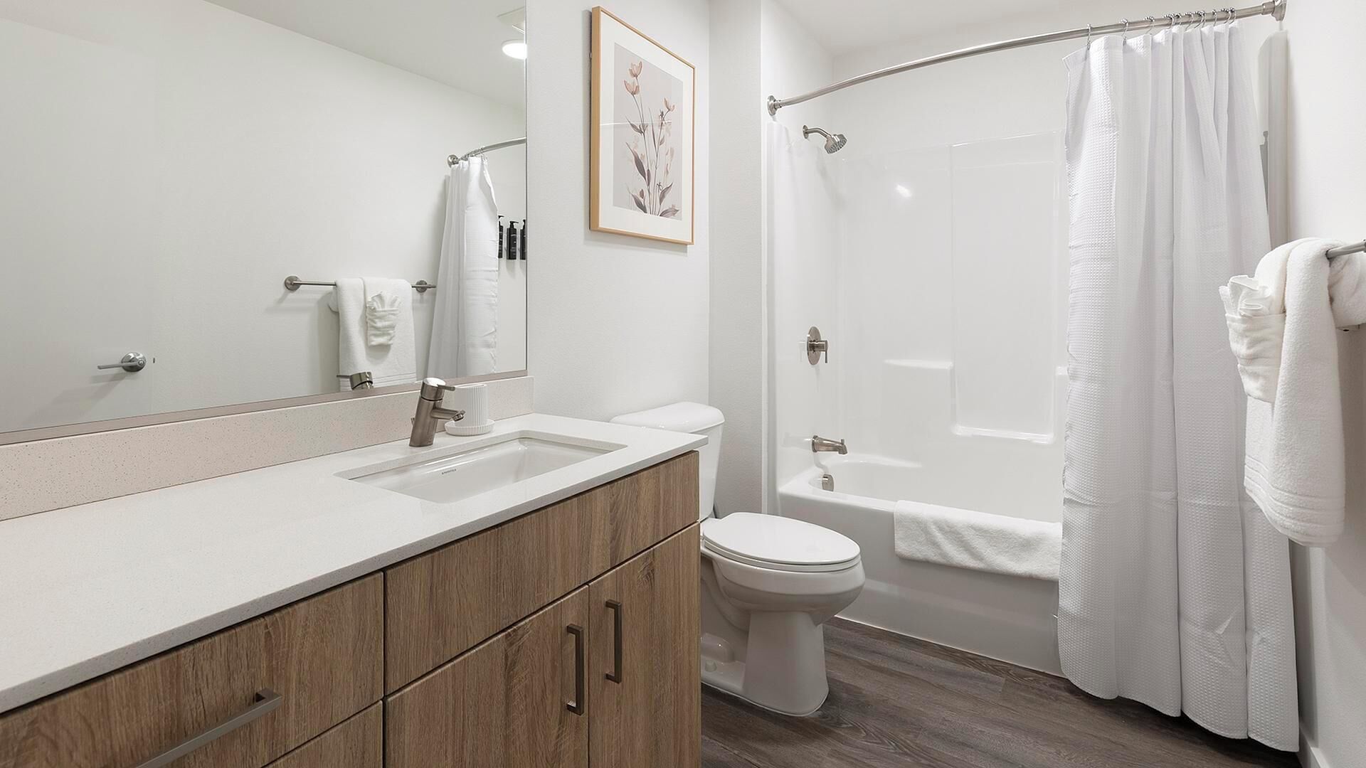 Un bany modern amb un mirall gran, un lavabo, un vàter i una zona de dutxa.