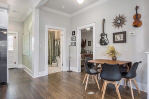 Un comedor con mesa de madera y sillas negras, una guitarra y un reloj de sol en la pared.