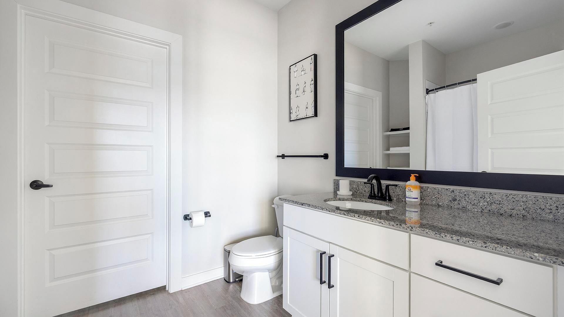 A bathroom with a white toilet, a sink with a black faucet, and a large mirror above the sink.