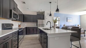 Une cuisine moderne avec des meubles de couleur sombre, des appareils en acier inoxydable et un îlot central.