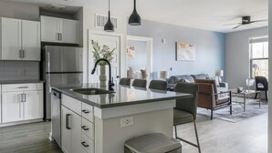 Een moderne keuken met een centraal eiland, witte kasten en roestvrijstalen apparatuur.