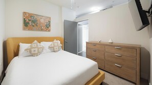 A bedroom with a bed, a dresser, a painting, and a door leading to another room. - Landing | Chic 1BD, Clubhouse, Gym (Richmond)