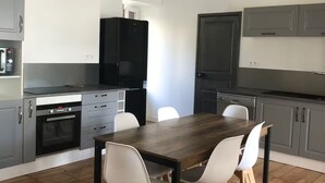 Une cuisine moderne avec des meubles de couleur grise, une table à manger en bois et des chaises blanches.
