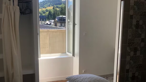 Une chambre avec un lit, une fenêtre, un espace douche et une vue sur l’extérieur.