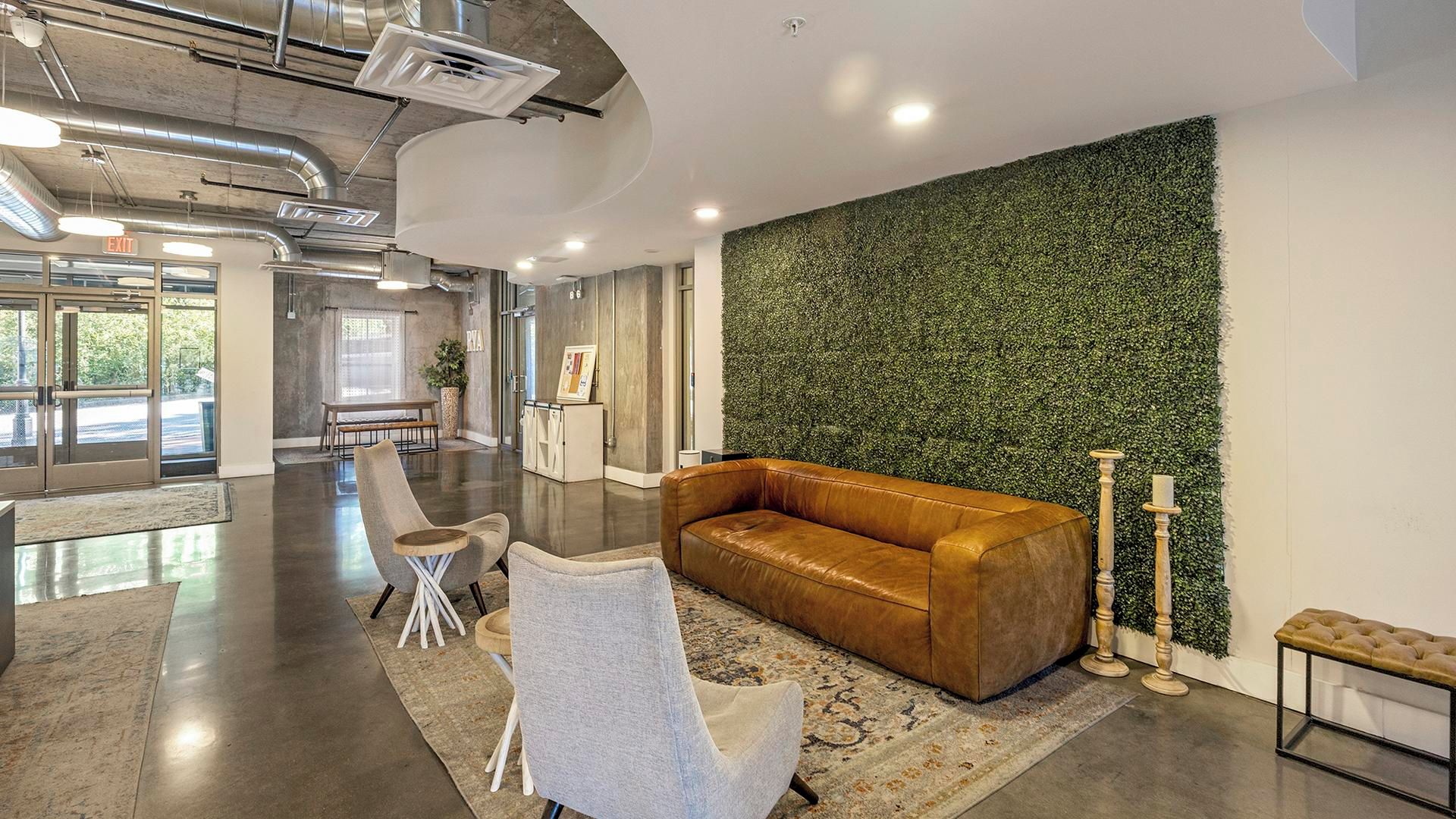 A spacious lobby with a leather sofa, a white armchair, and a patterned rug.