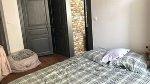 Ein Schlafzimmer mit Bett, Haustierbett, einer Tür und einer Ziegelwand.