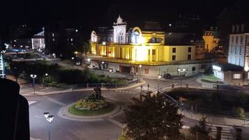 A nighttime view of a cityscape with a roundabout, illuminated buildings, and a bridge.